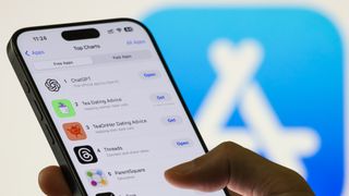A person uses a smartphone showing the Apple App Store top charts with ChatGPT ranked as the number one free app, followed by other popular applications including Grok, on August 12, 2025.