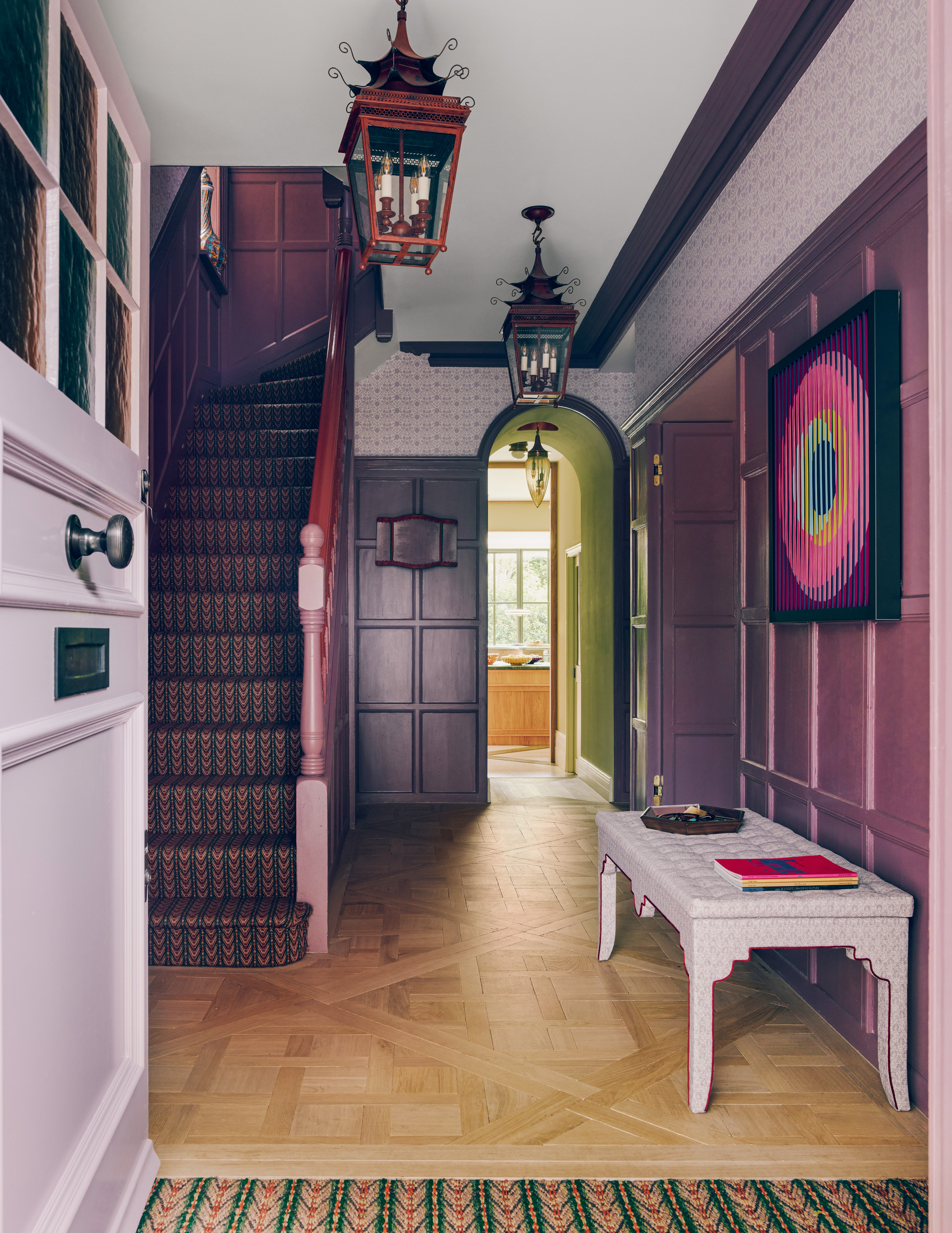 Purple hallway with darker painted panelling, lilac wallpaper and front door, and parquet floor