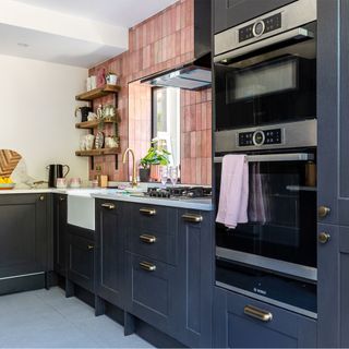 black kitchen cabinets with pink tiles and butler sink