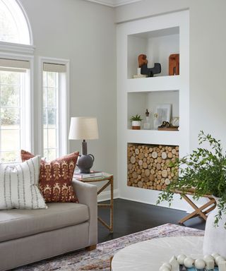 living room painted white with neutral sofa and built in shelving with log storage
