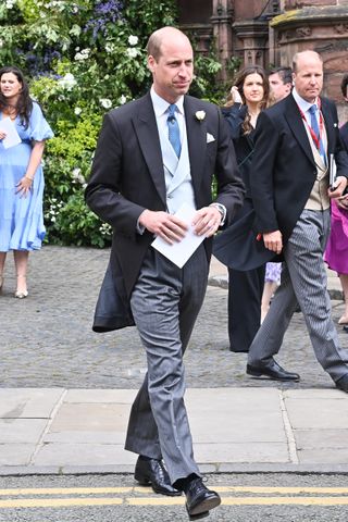 Prince William wearing a three-piece suit walking outside the church at the wedding of the Duke of Westminster in 2024