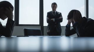 Boardroom with frustrated people with their heads in their hands
