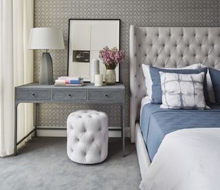 A bedroom with a dresser and ottoman placed beside the bed for vanity dressing are
