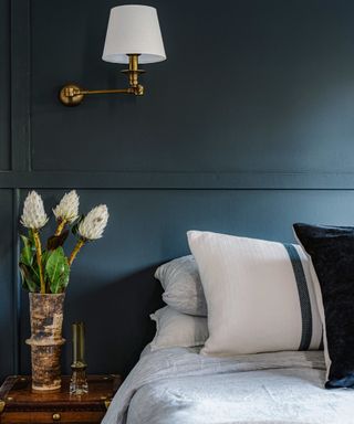 bedroom with dark gray panelling, neutral bedlinen and wall light