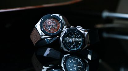 Two watches resting on a black background