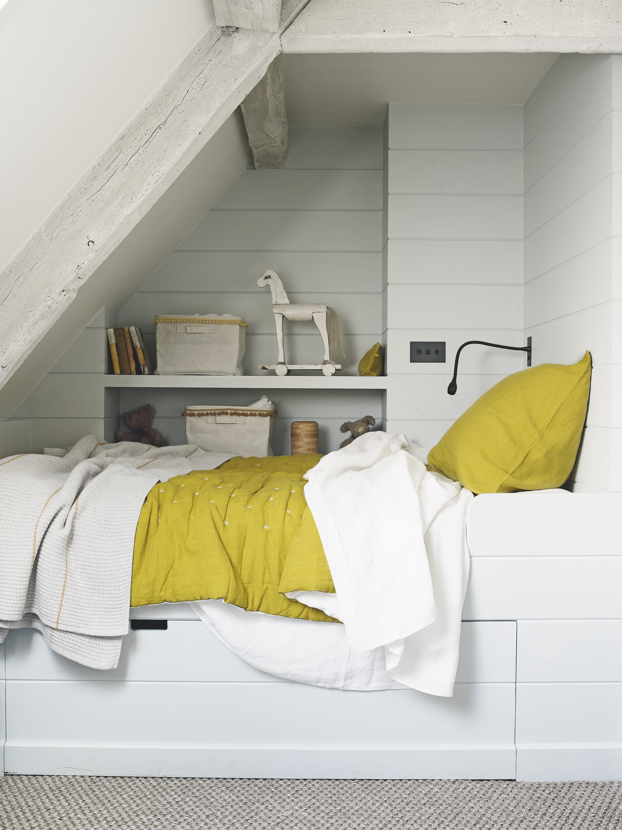 kid's attic room with bed and shelves under sloping ceiling