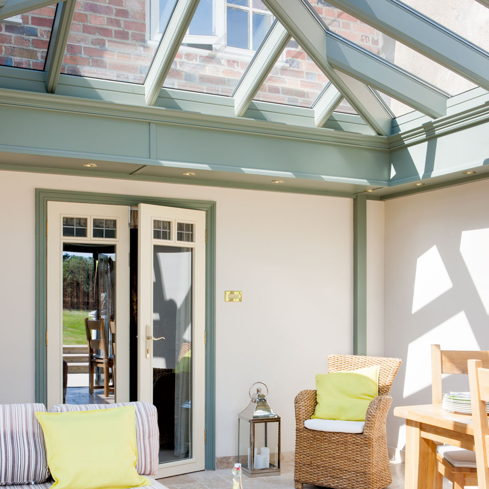 A conservatory with green structured roof lantern and cream walls