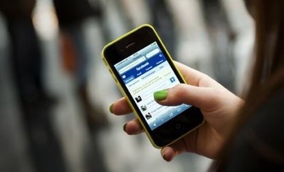 A teen checks Facebook on her iPhone