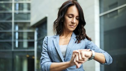 A Gen X woman looks at her watch.