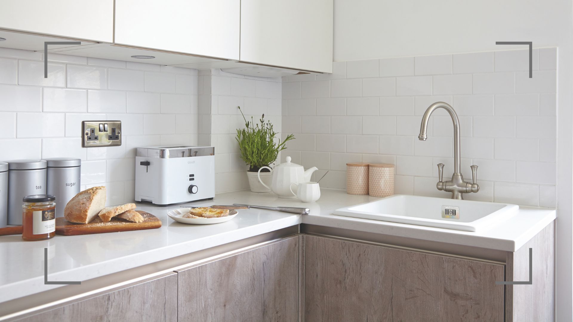Corner of a small white kitchen with lime-washed cabinets on the bottom half of the kitchen