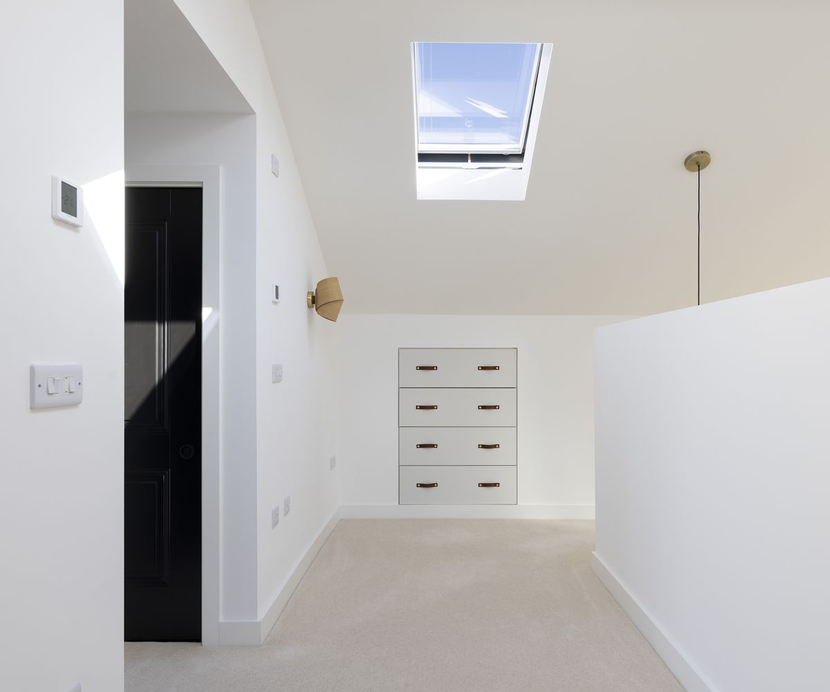 hallway with beige carpet and white walls and roof sky light