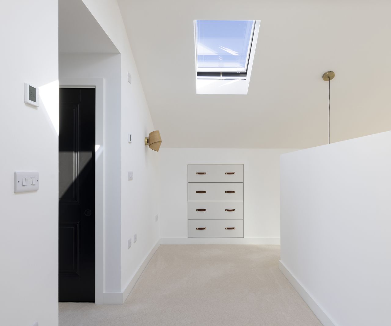 hallway with beige carpet and white walls and roof sky light