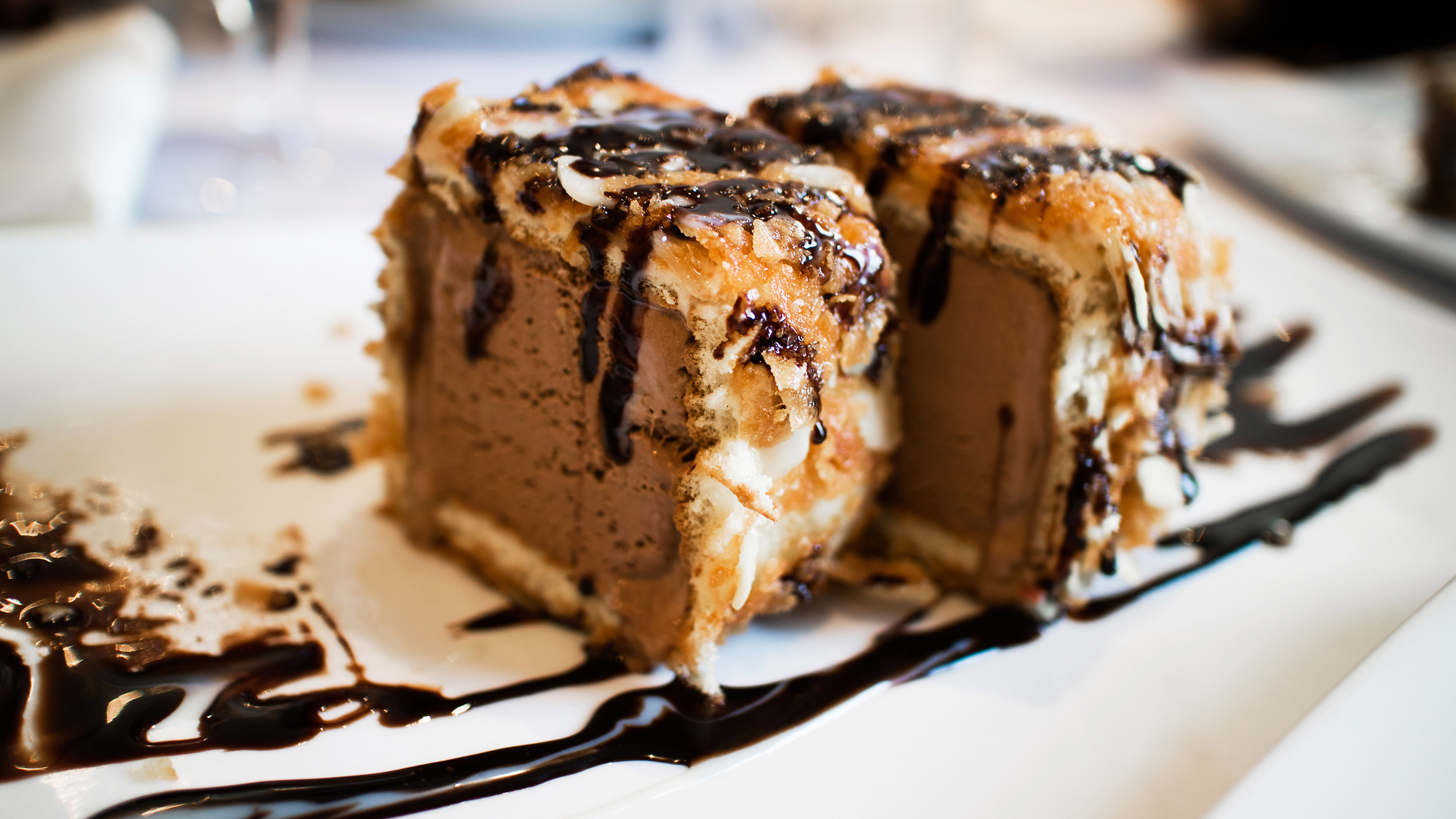 Deep fried ice cream on a plate drizzled in chocolate sauce