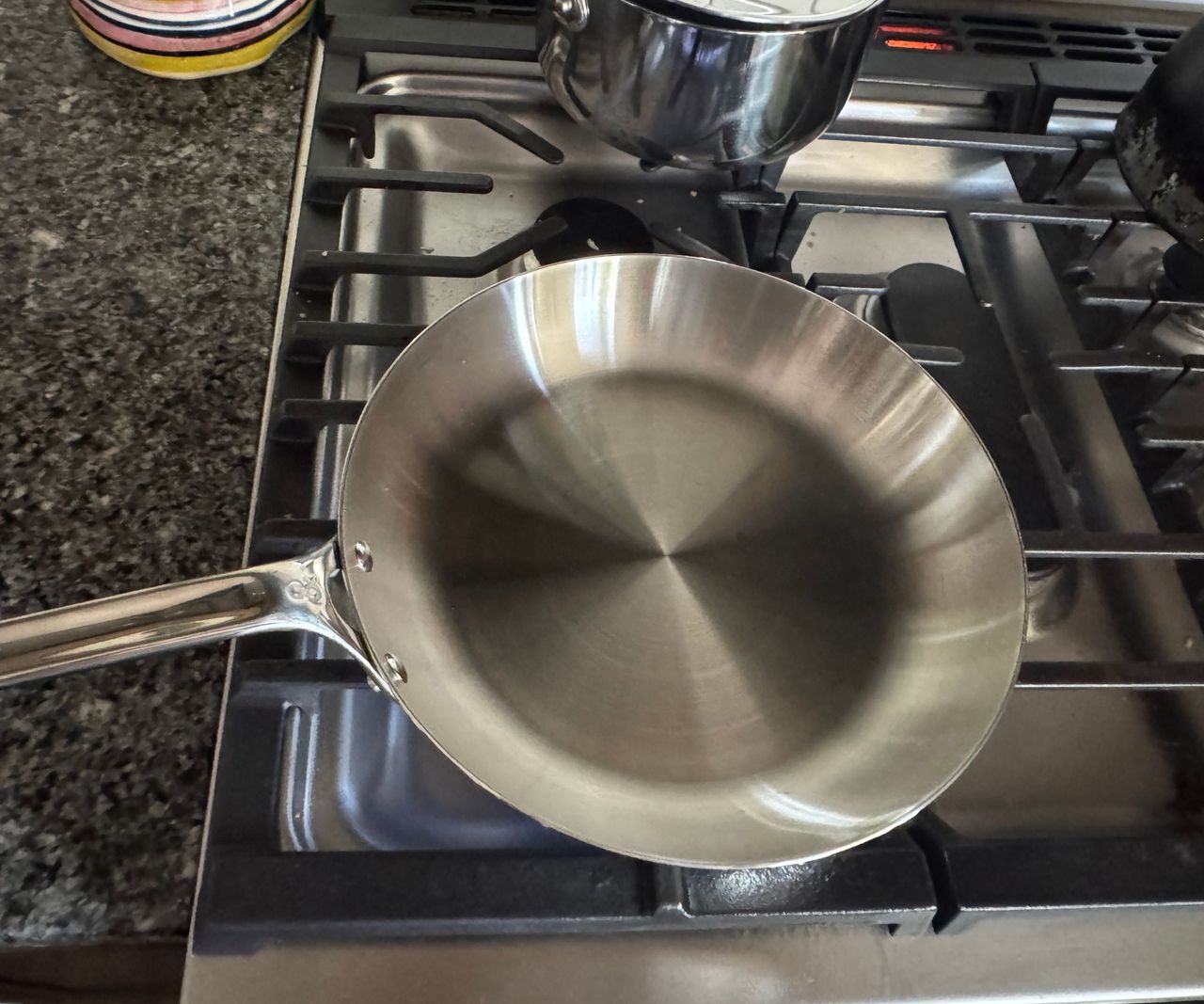 A small stainless steel frying pan on a gas stove