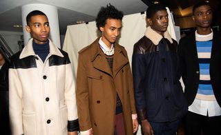 Group of male models in thick coats looking away from camera