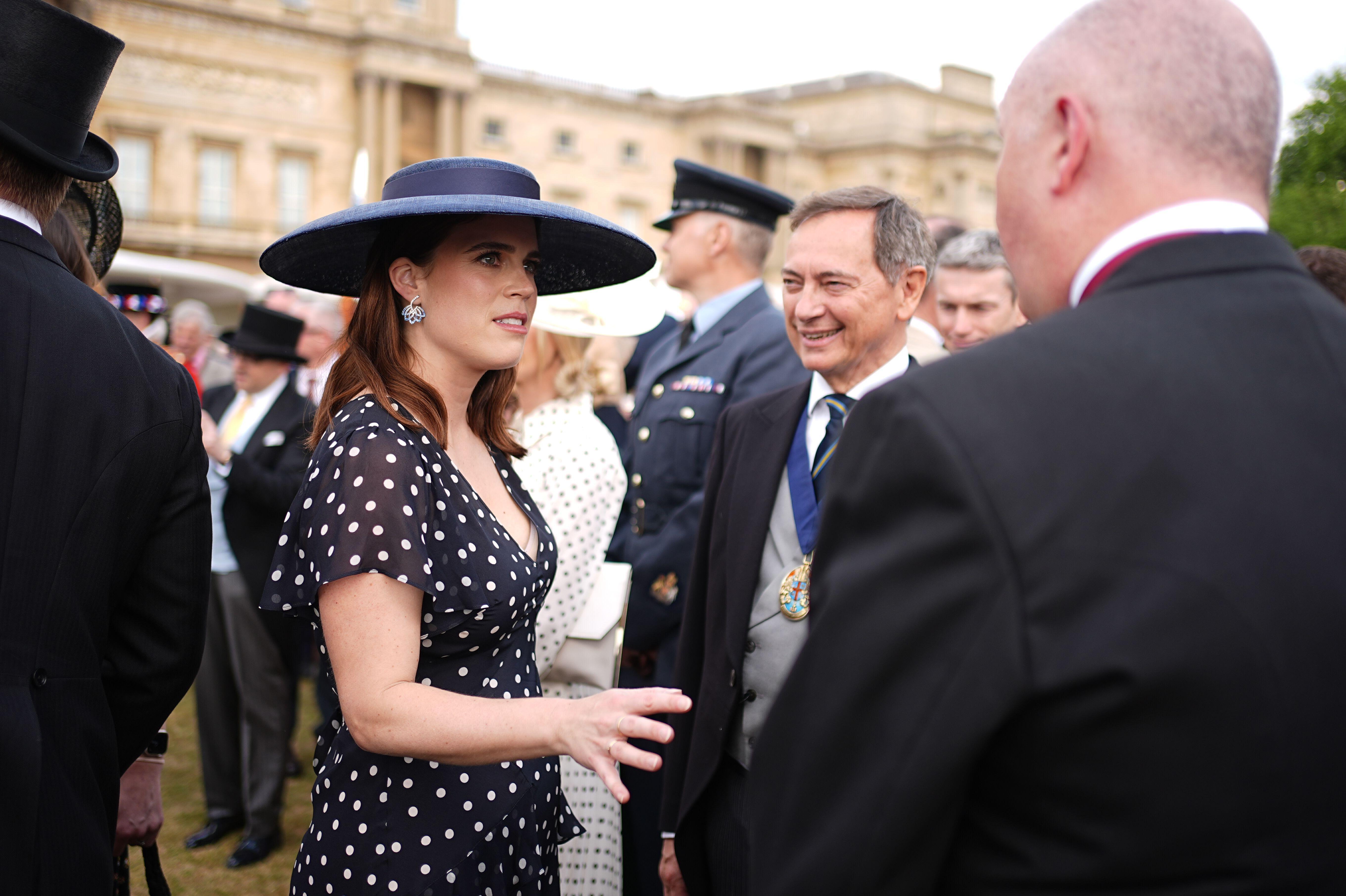 Princess Eugenie wearing a navy polka dot dress and blue hat at a garden party