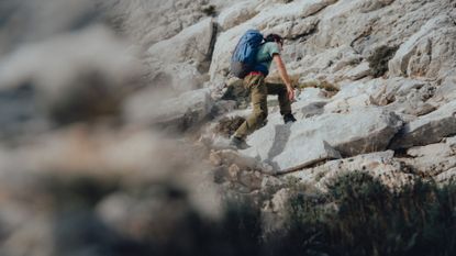 best walking trousers: Man walking up the mountain wearing hiking gear