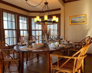 Wooden dining room table set up for a Thanksgiving dinner including pumpkin pie