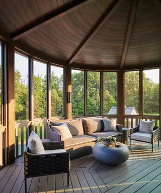screened porch with wooden ceiling, chunky chairs, neutral sofa and small round gray table
