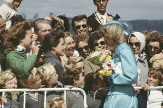 Princess diana wearing a blue dress and hat while talking to a huge crowd of fans in 1983 Australia