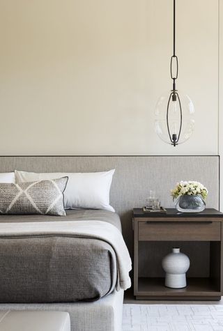 Beige bedroom with large grey headboard and white bedding
