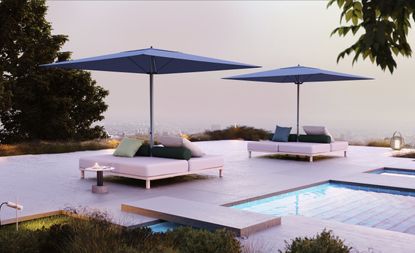 ‘Meteo’ garden parasol by Konstantin Grcic for Kettal. Two blue parasols with white sofas below them next to a pool with a view of the city below.