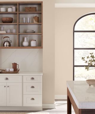 corner of kitchen with whit cabinets, beige wall and large arched window