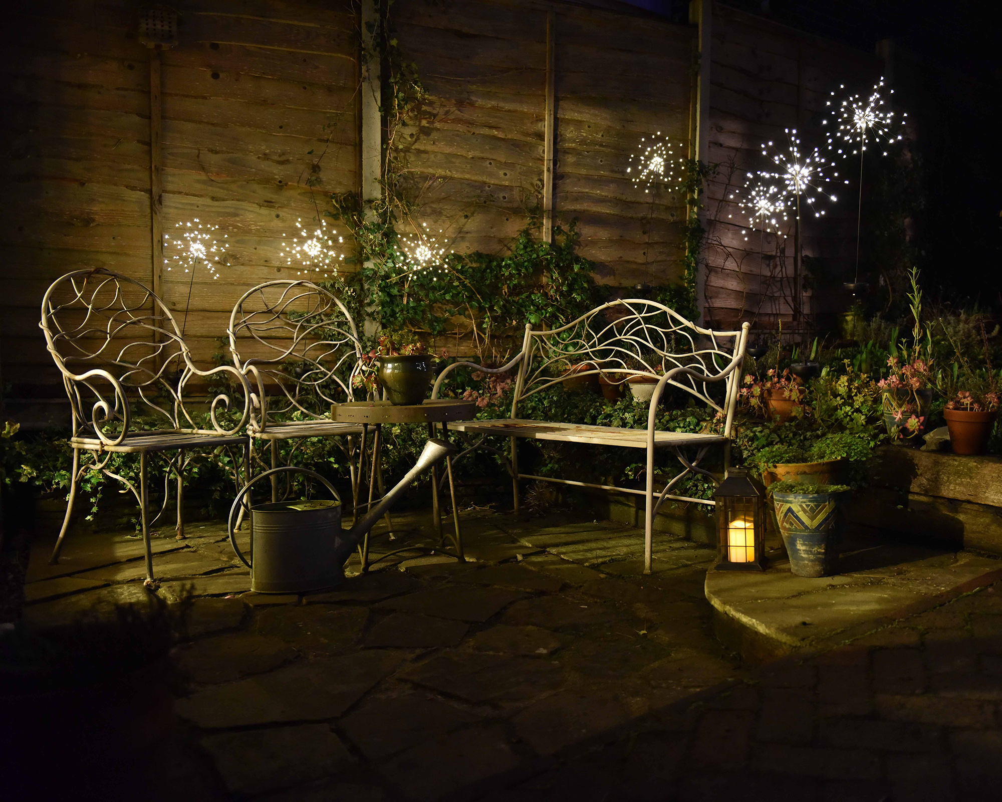 Twinkle solar lights stuck in beds around a patio area lit up at night