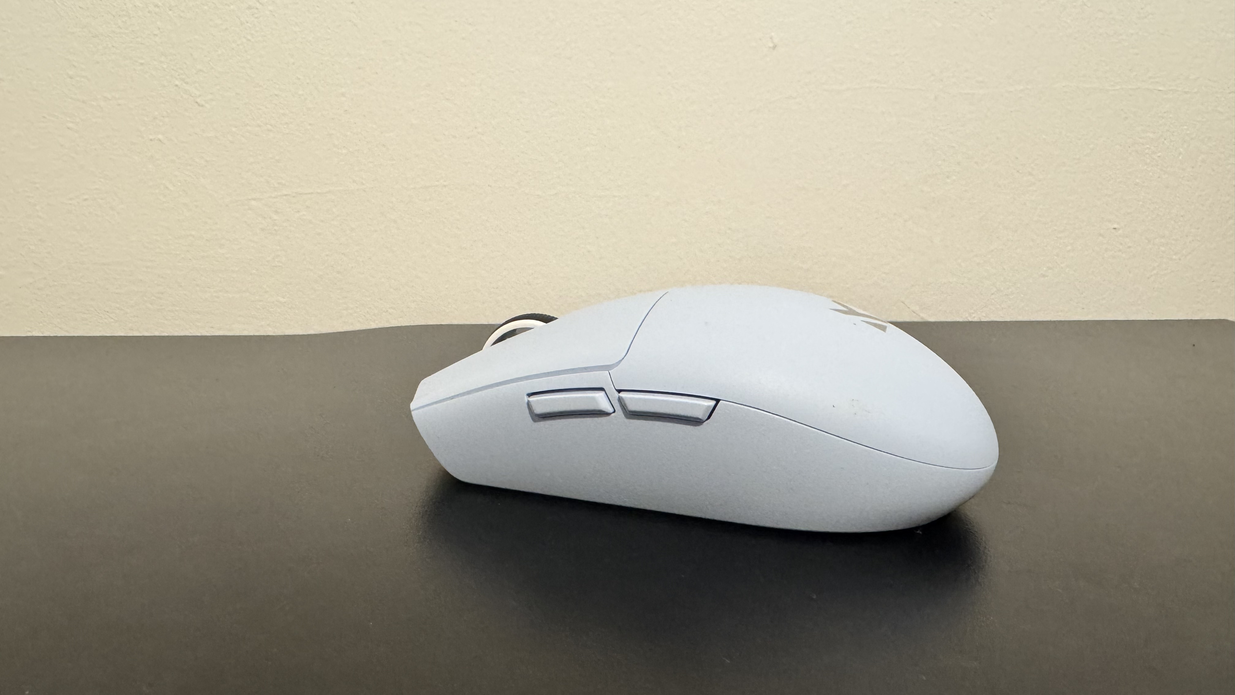 The blue Mchose G3 V2 gaming mouse from the left side on a black desk