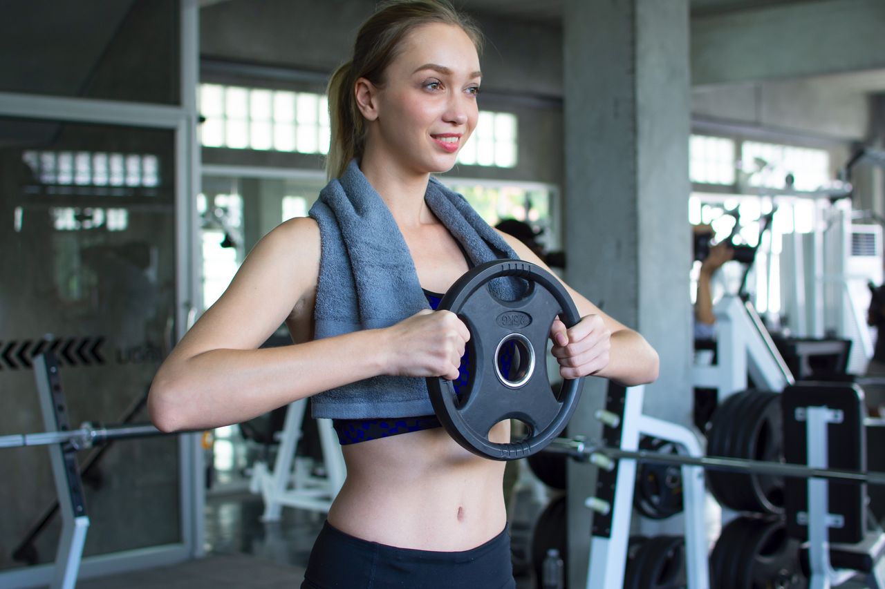 A woman exercising in the gym with a weight plate 