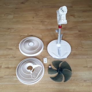 The white pedestal EcoAir Kinetic fan being unboxed and assembled on a wooden floor