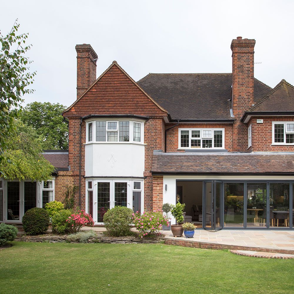 home exterior with brick wall green lawn and potted plants