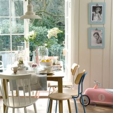 dining table beside open French patio doors with a pink child's toy car on the floor