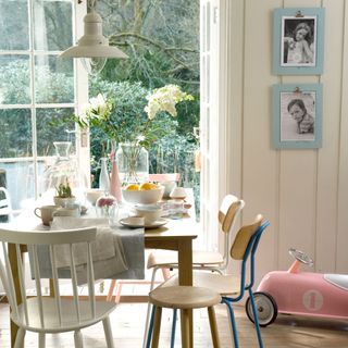 dining table beside open French patio doors with a pink child's toy car on the floor