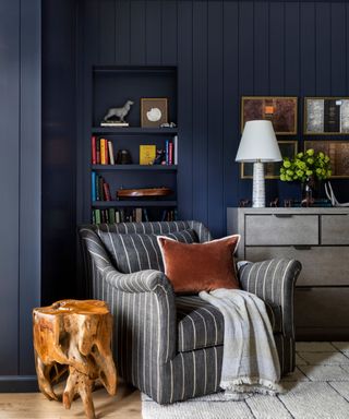 Dark blue panelled reading nook with gray and white stripe chair