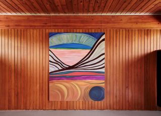 A wood paneled wall with a big colourful painting