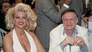 (L, R) Anna Nicole Smith and Hugh Hefner seated at a table, seen in Anna Nicole Smith: You Don't Know Me