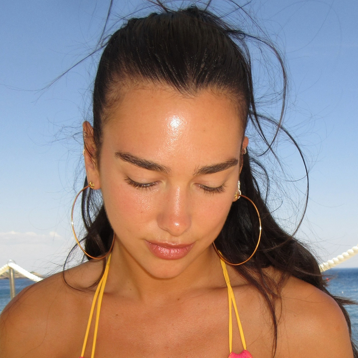 dua lipa wears a yellow bikini with pink lace trim.