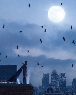 Winged superhero standing on a building overlooking the London skyline with birds flying overhead