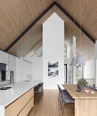 kitchen with pale wood units and vaulted ceiling and white countertops