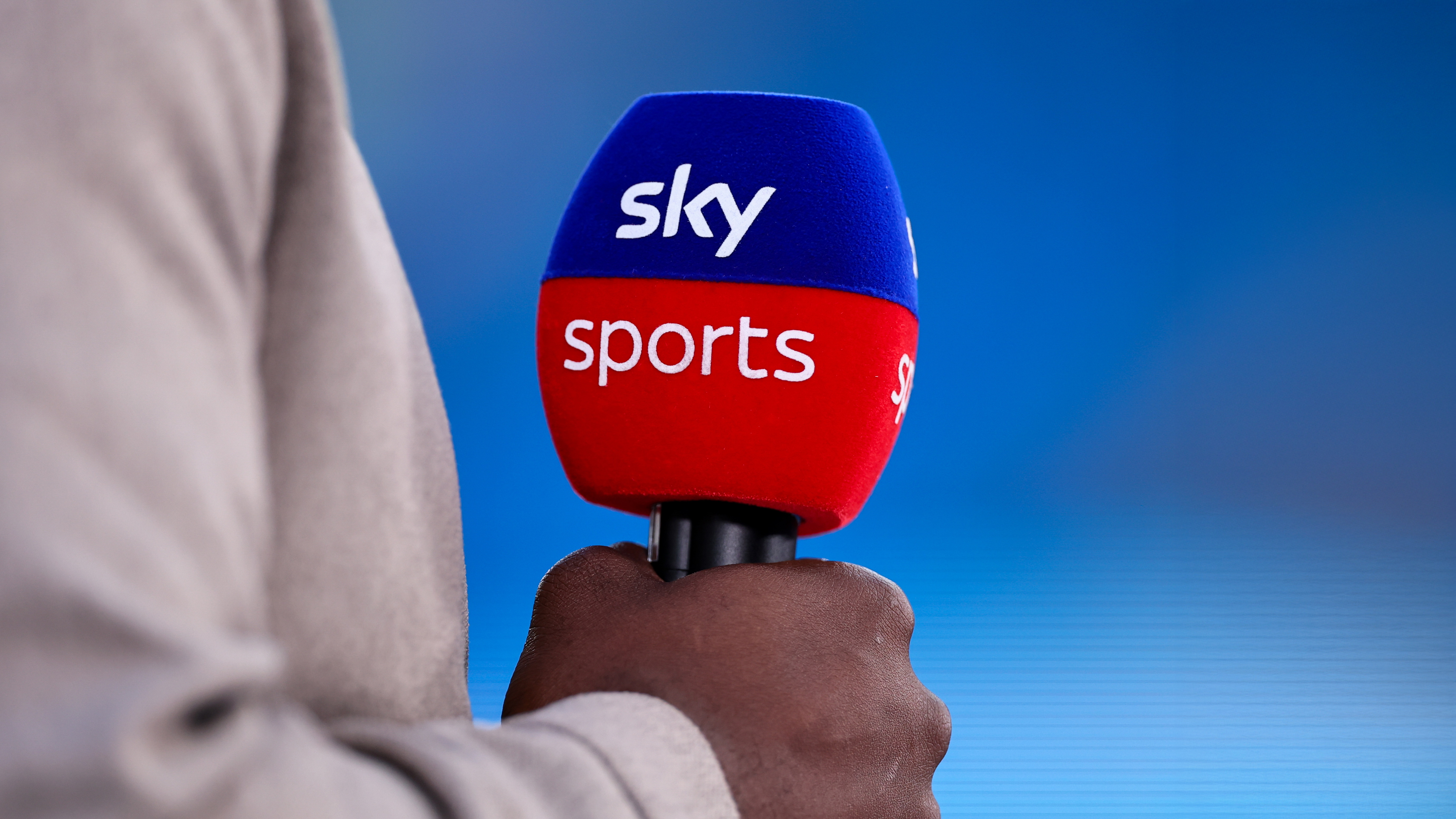 Sky Sports microphone in man's hand against a blue background