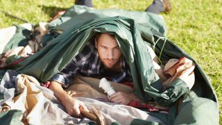 Man lying under collapsed tent in field