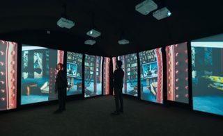 Two men standing in a room with interactive walls with displays coming from the white projectors in the ceiling