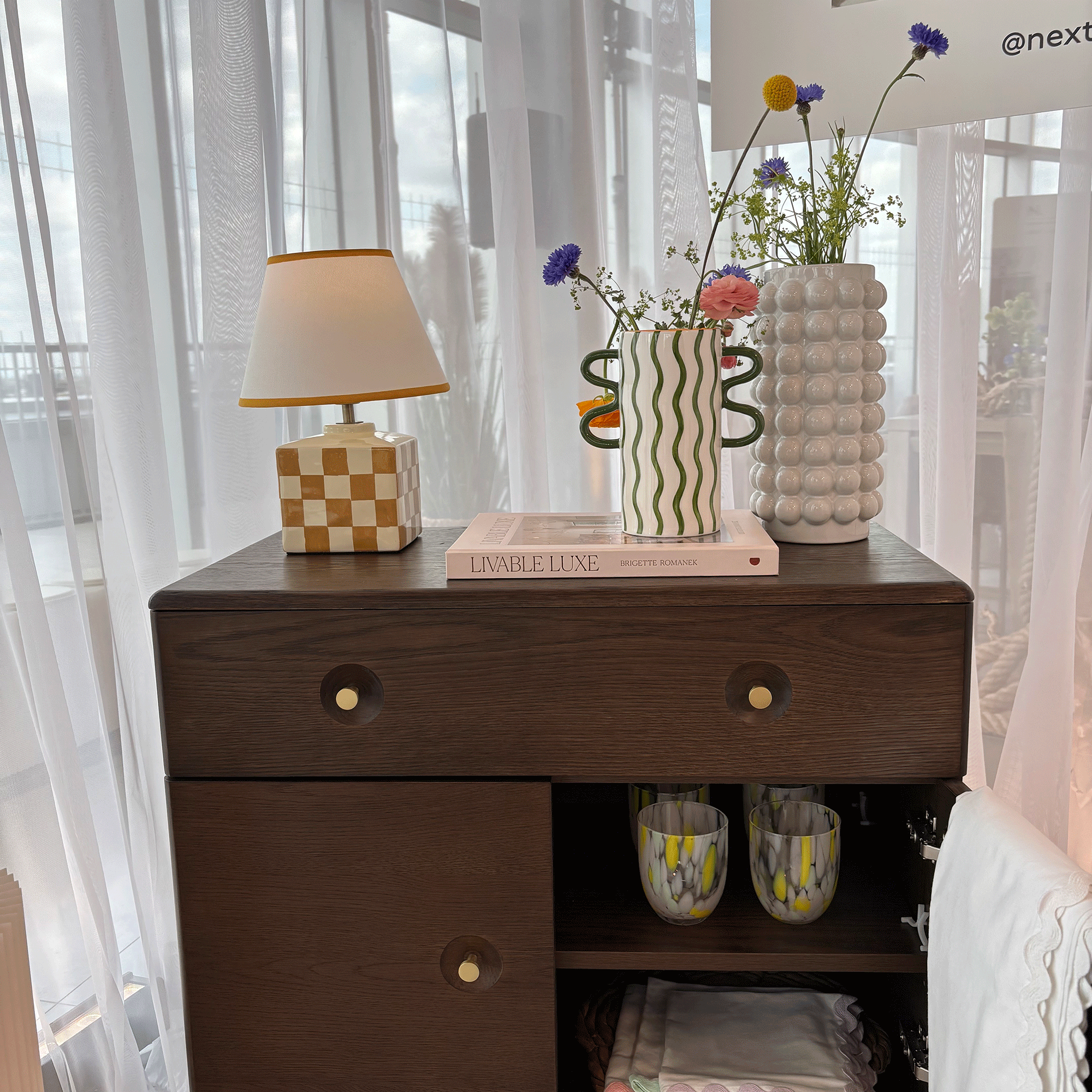 Yellow check table lamp, green wriggle vase and bubble vase on a dark wood side table