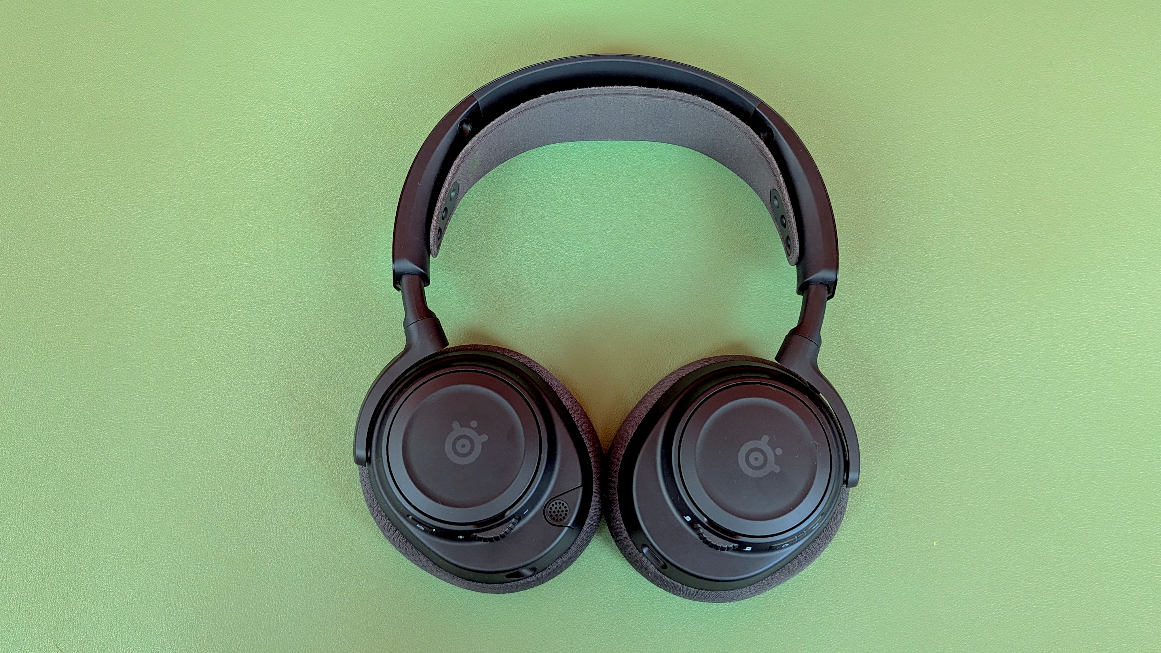 Black headphones resting on a green surface