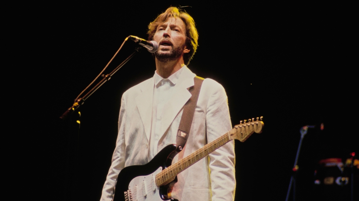 British singer, songwriter and guitarist Eric Clapton, wearing a white blazer over a white shirt, with his Fender Stratocaster, 'Blackie', in concert, circa 1990