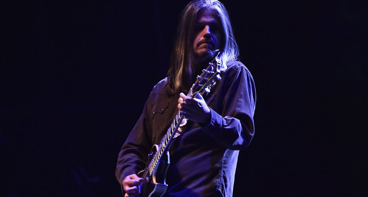 Adam Jones of Toll plays his Silverburst Les Paul Custom on a darkly lit stage in 2017.