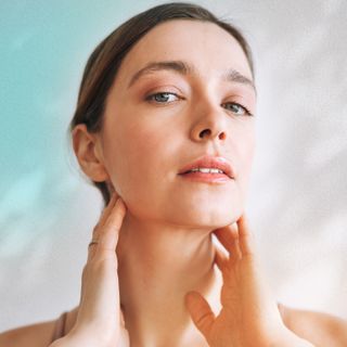 woman touching her neck in front of a white background