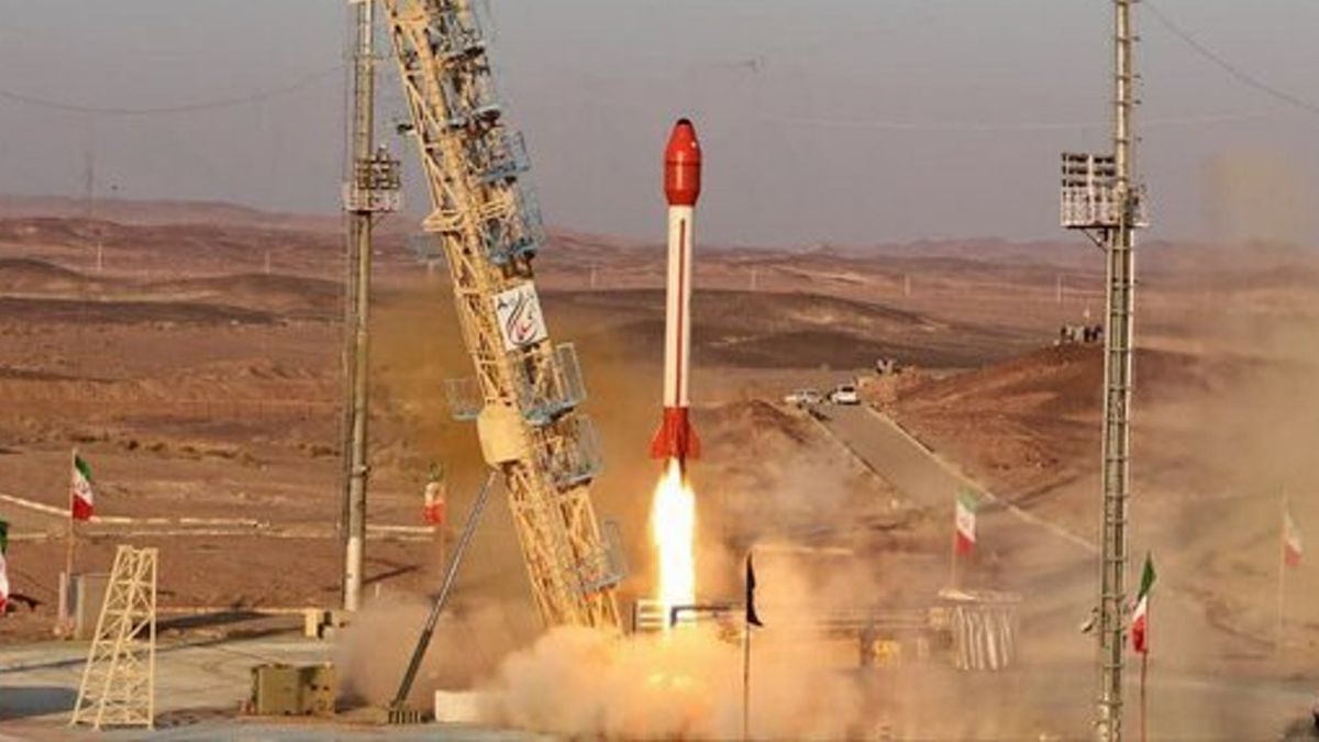 a rocket topped with a red capsule launches in the desert