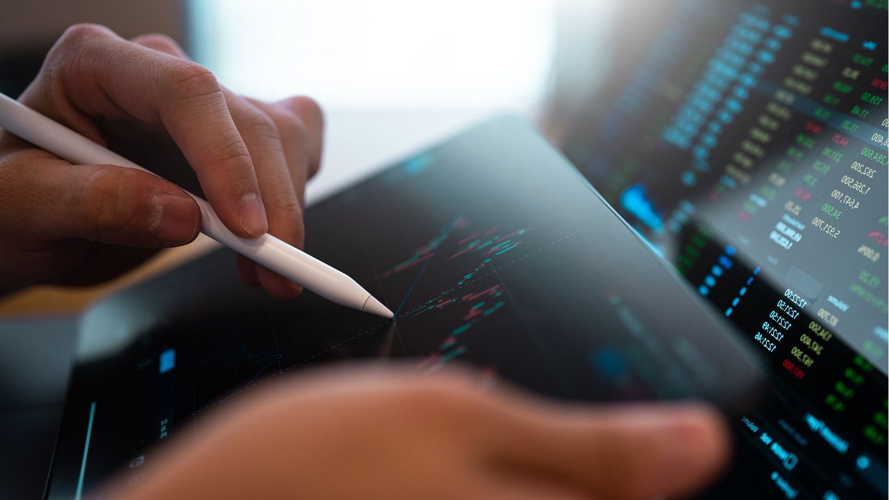 An investor tracks the stock market&#039;s ups and downs on a tablet.